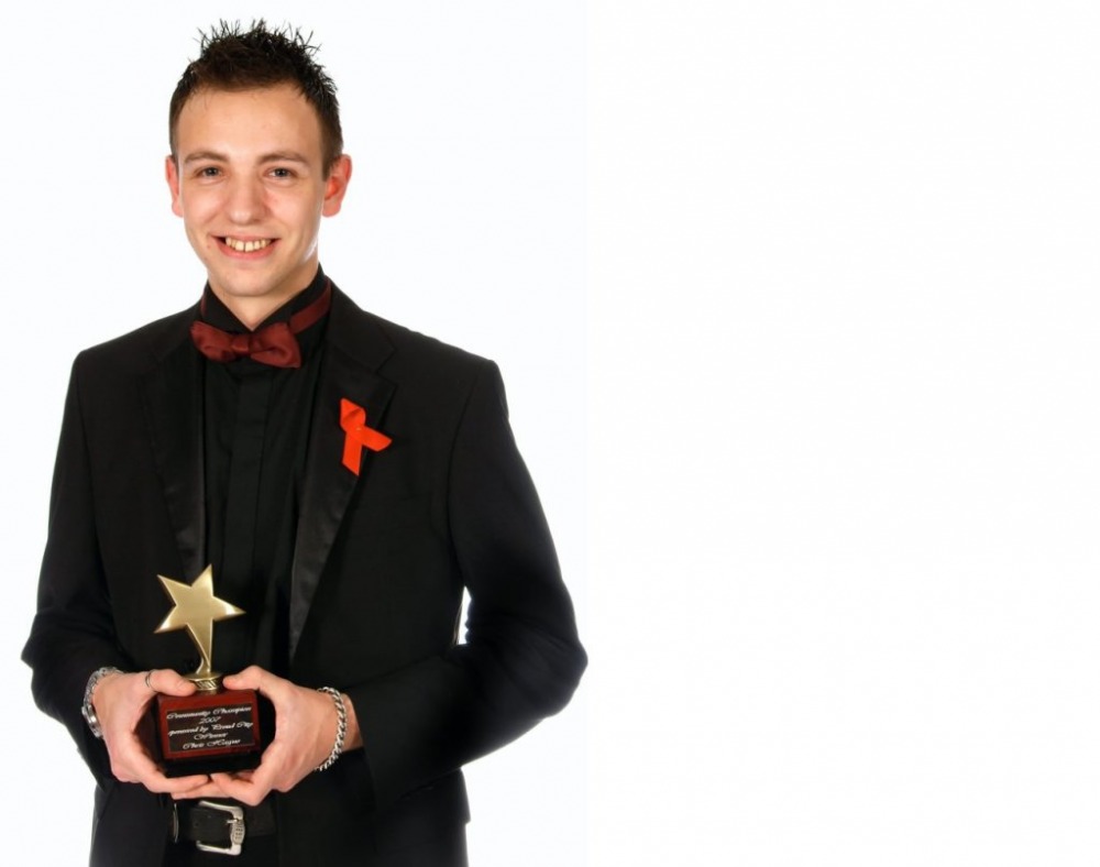 Young man in a suit holding an award at an event