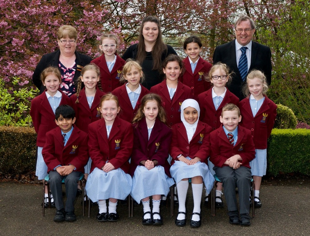 A full class group photo outdoors, pupils in red uniforms with their teachers